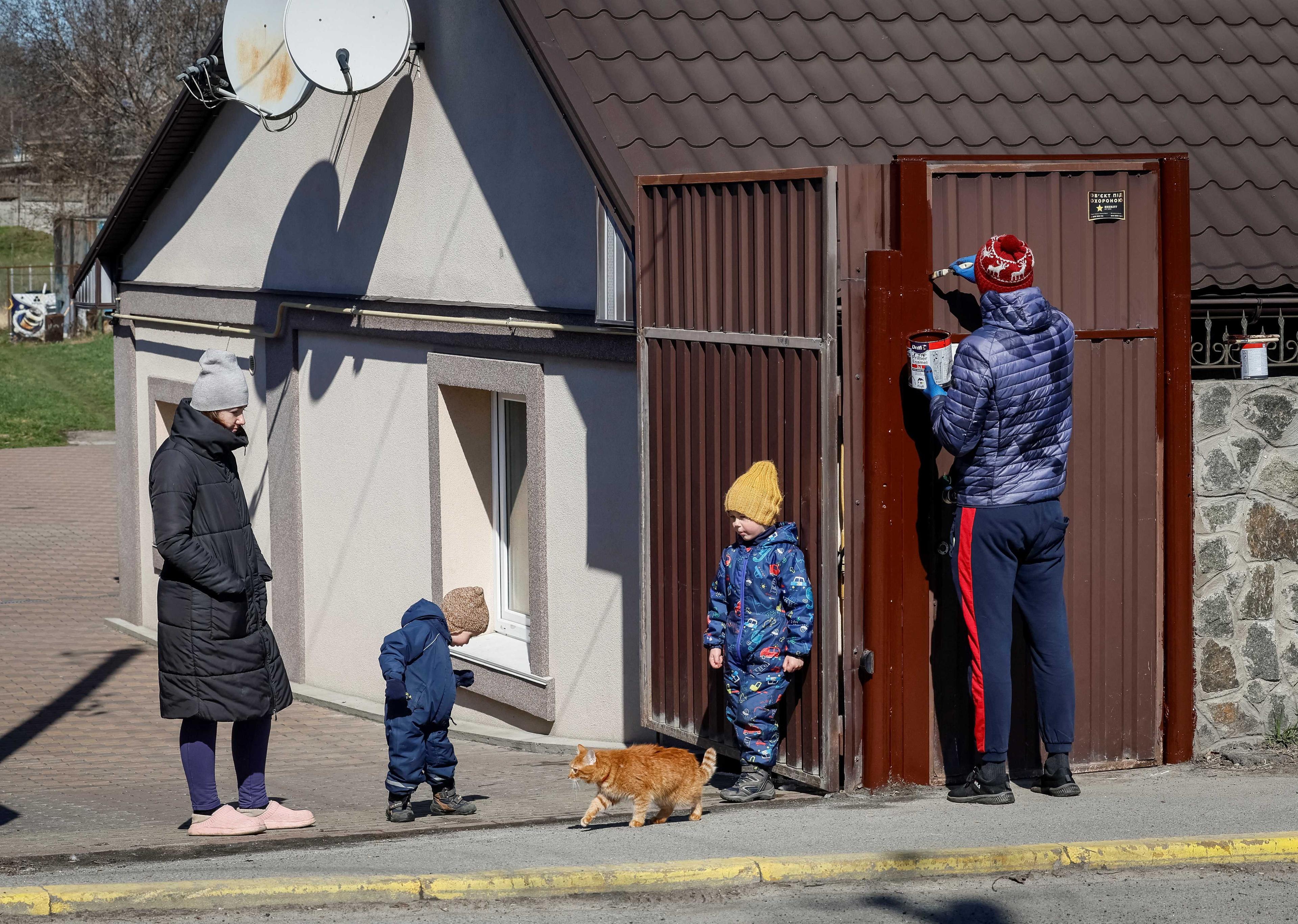 Sebuah keluarga mengecat pintu pagar rumah mereka. Tentera Rusia membunuh orang awam semasa pendudukan mereka di bandar Bucha, 30 Mac. Gambar: Reuters