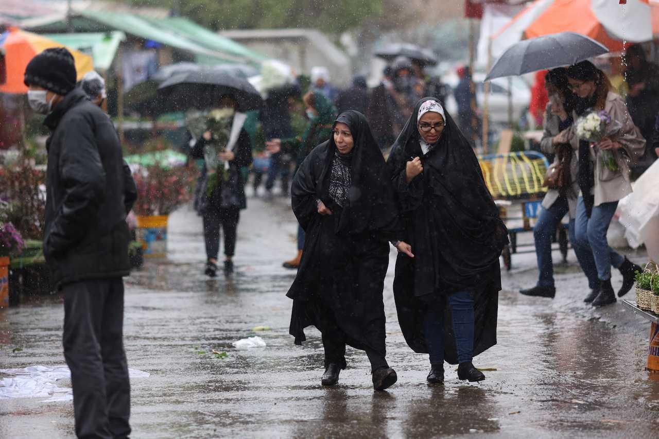 Iranian women walk through the rain in a flower market, in Tehran, Iran, March 16. Photo: Reuters