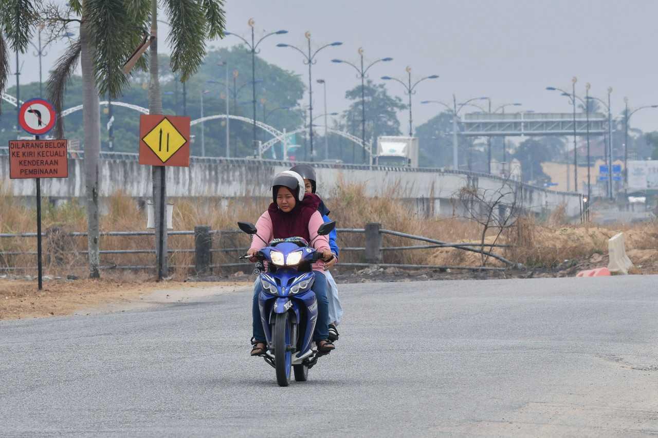 A motorcyclist makes her way through hazy conditions at Jambatan Sultan Yahya Petra in Kota Bharu, April 17. Photo: Bernama