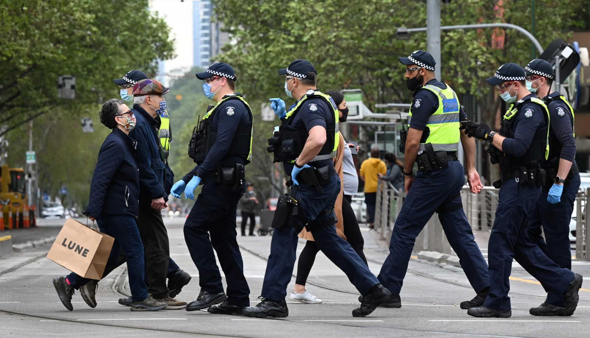 People carry their shopping as police patrol in Melbourne on Sept 30, 2021. Photo: AFP 