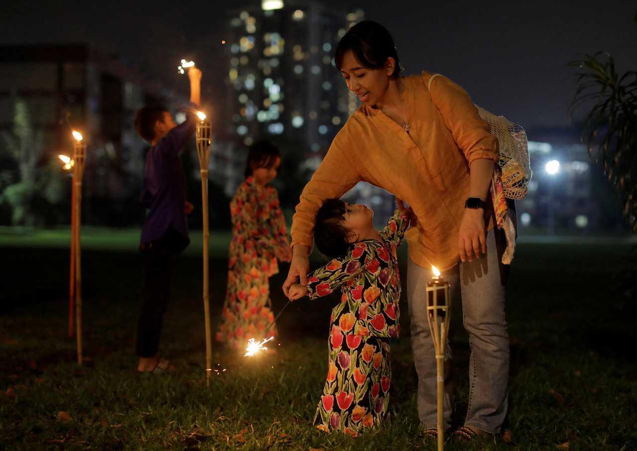 A woman supervises her daughter as she plays with a sparkler ahead of the Hari Raya Aidilfitri celebration in Kuala Lumpur. 