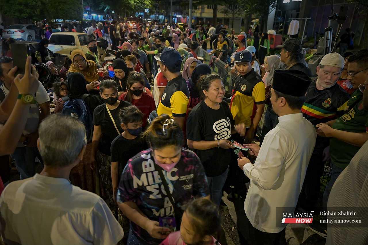At night, the streets come alive as individuals and organisations gather to distribute aid and packets of money for Raya. 