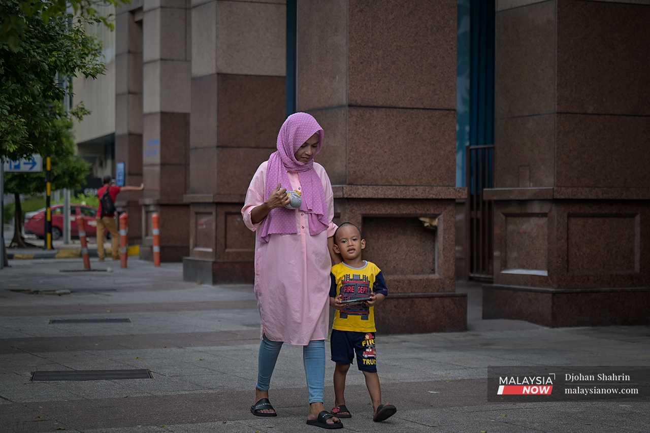 Ana and her son walk hand in hand through the streets of Kuala Lumpur.