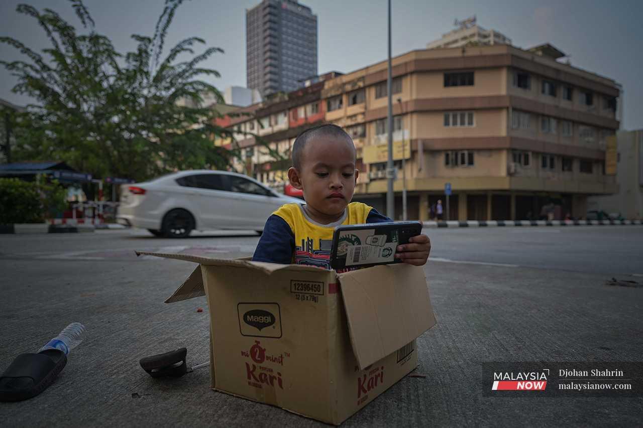 Her son sits in a box, waiting for her to finish her daily tasks. 