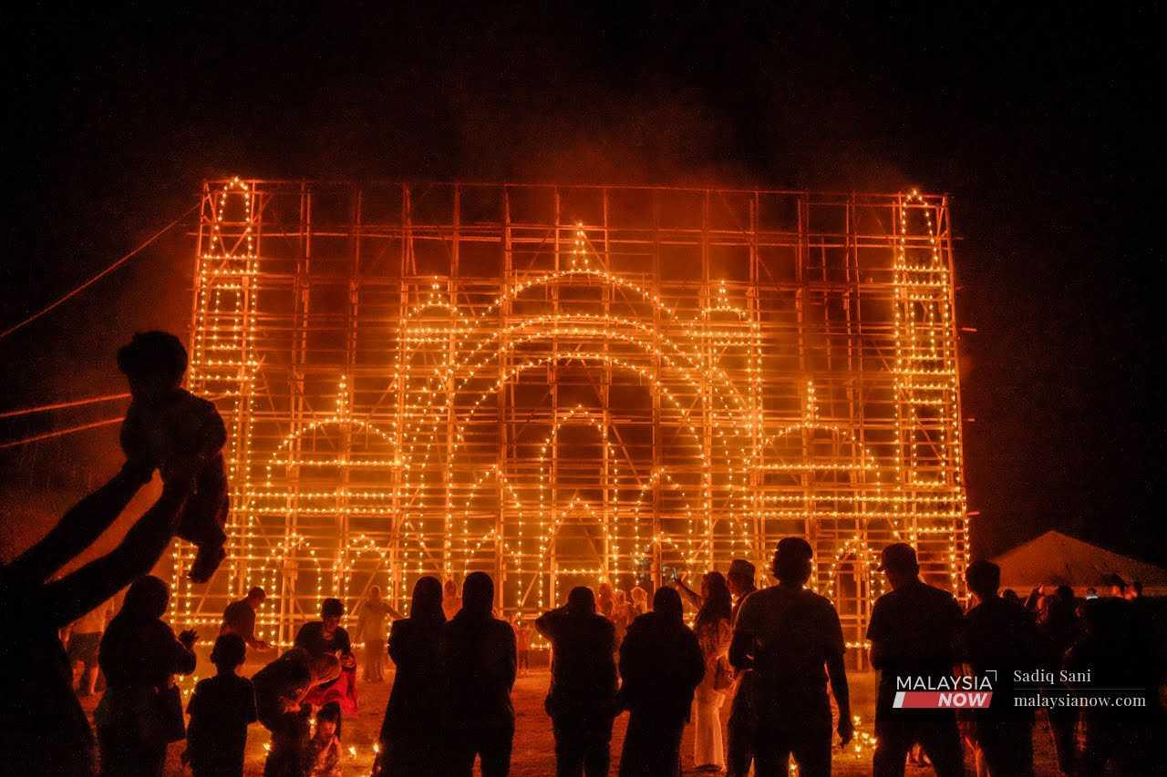 Visitors admire a replica of the Federal Territory Mosque made out of thousands of tiny oil lamps in Kampung Ribu, Kuala Kangsar.