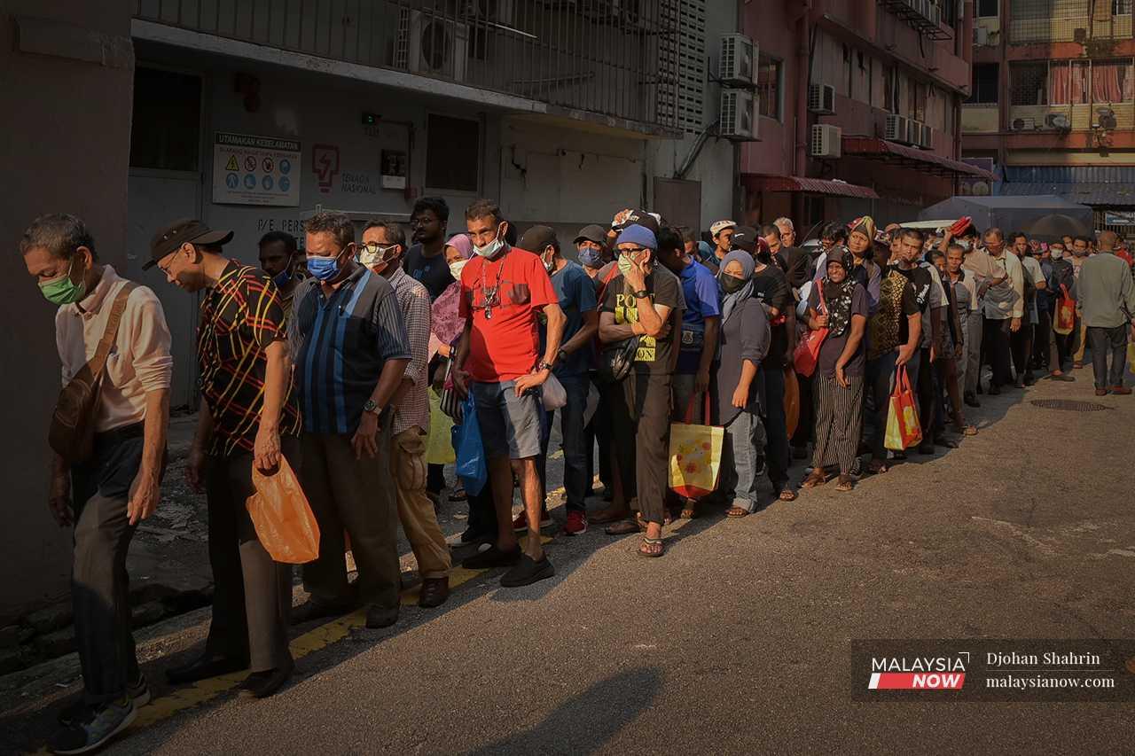 Scores of others like her and her family queue at the back of Lorong Haji Taib in Chow Kit, waiting to receive donations of food from a charity outfit, the Ar Riqab Welfare Organisation. 