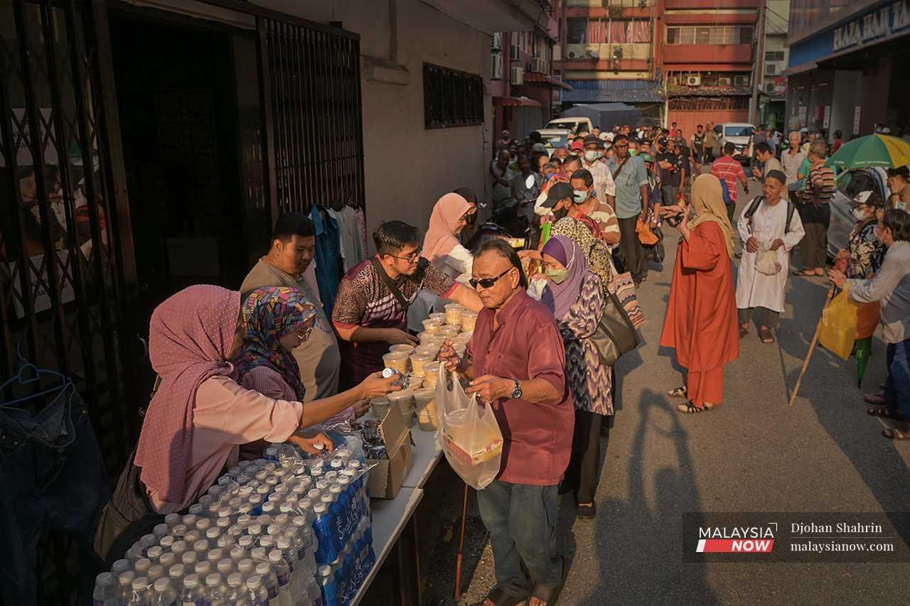Marziana (left) helps the organisation distribute packets of food to the urban poor in the area. 