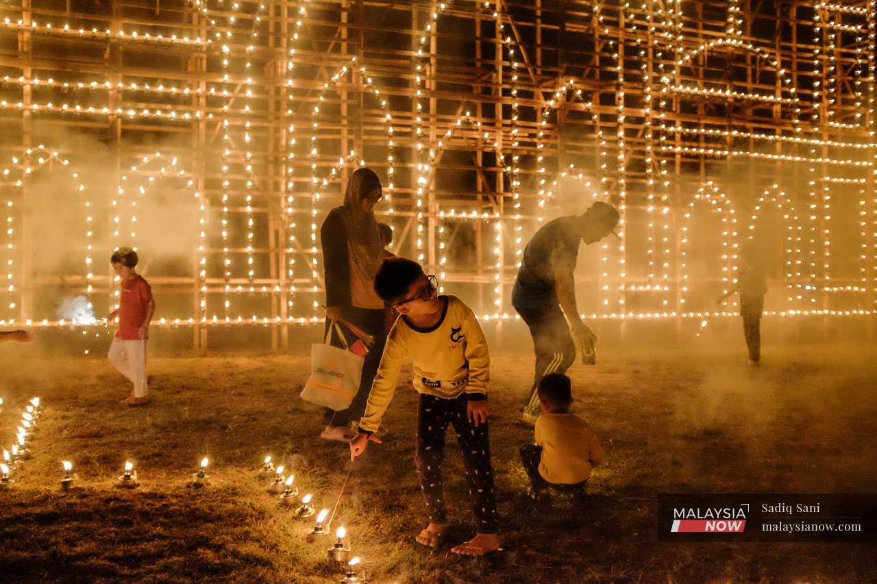 A boy lights a sparkler at one of the oil lamps. 