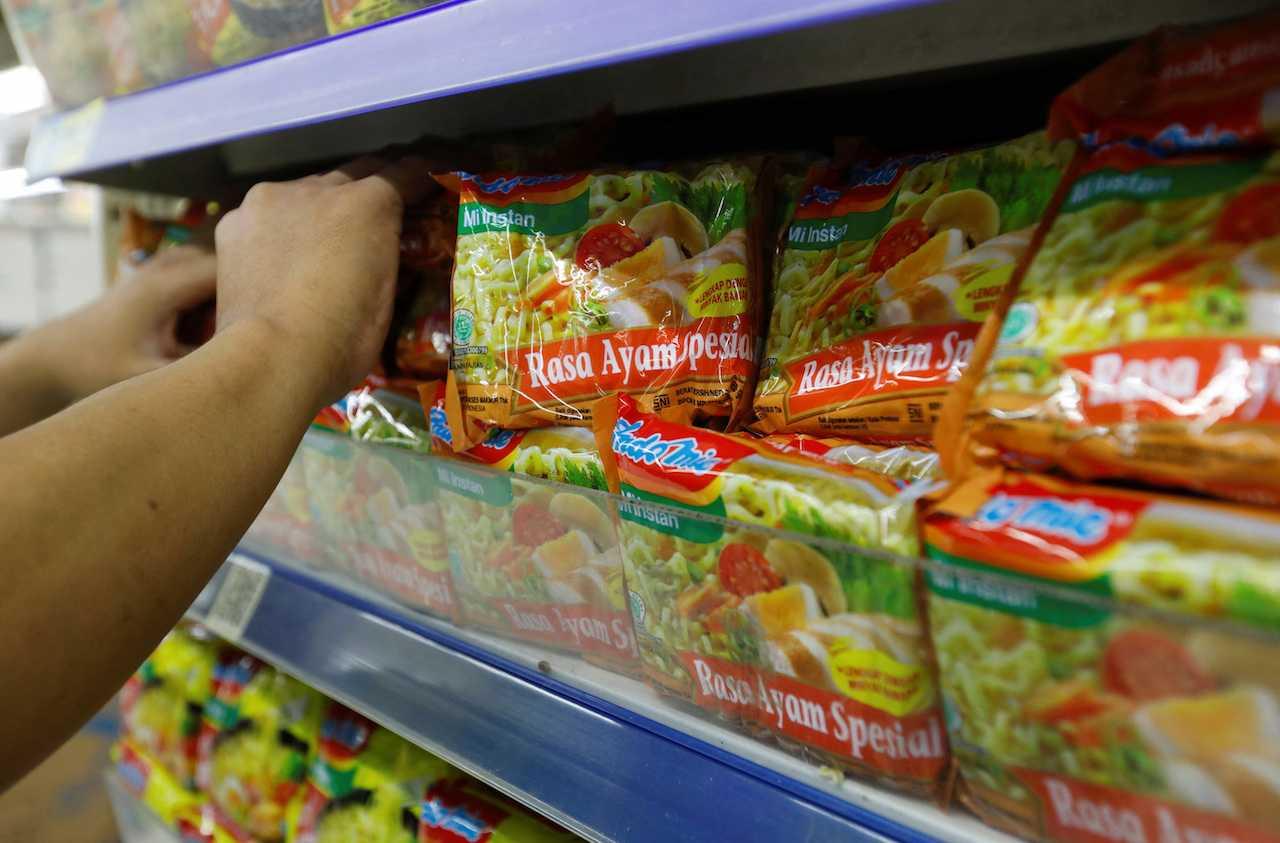 Seorang pekerja menyusun paket mi segera Indomie Perisa Ayam Spesial di rak sebuah pasar raya di Jakarta, Indonesia, 26 April. Gambar: Reuters