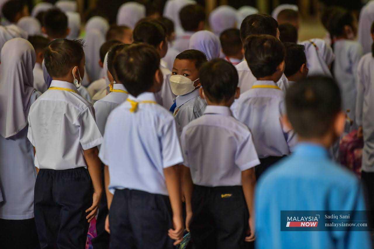 Seorang murid melihat ke belakang semasa perhimpunan di SK Taman Tasik di Ampang pada hari pertama pembukaan semula sekolah, 20 Mac.