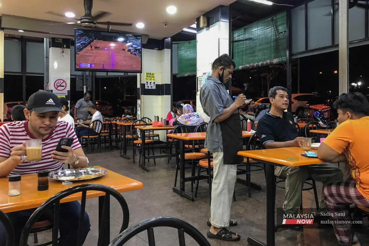 Gambar fail menunjukkan seorang pekerja mengambil pesanan daripada pelanggan yang datang ke kedai mamak.