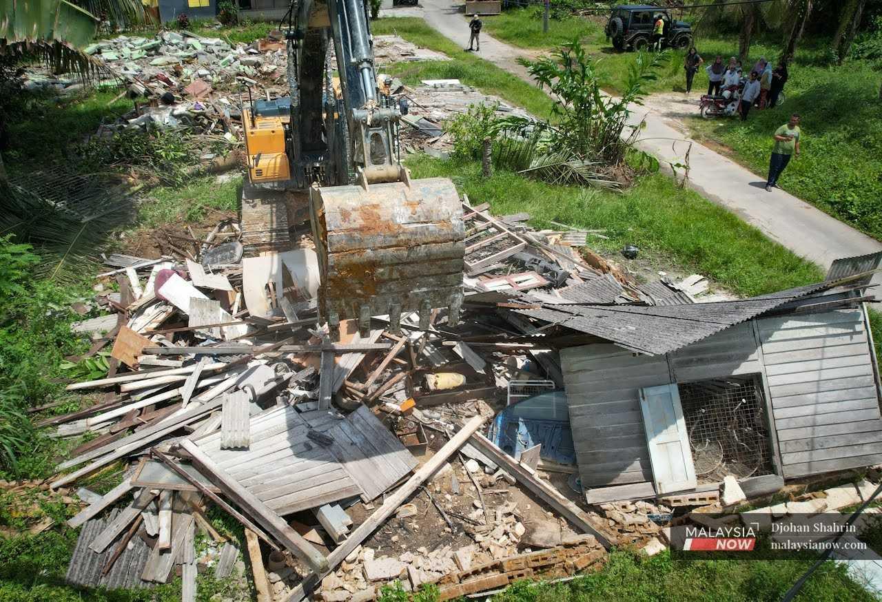 Villagers watch as a bulldozer tears down an unoccupied home in Kampung Koskan Tambahan, Rawang in Selangor.