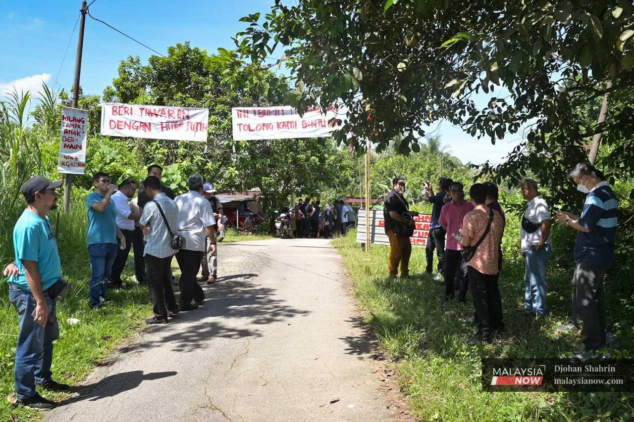 Residents gather at the entrance of the village to meet the landowners and officers from the Land and Mines Office as well as enforcement and court officers. 