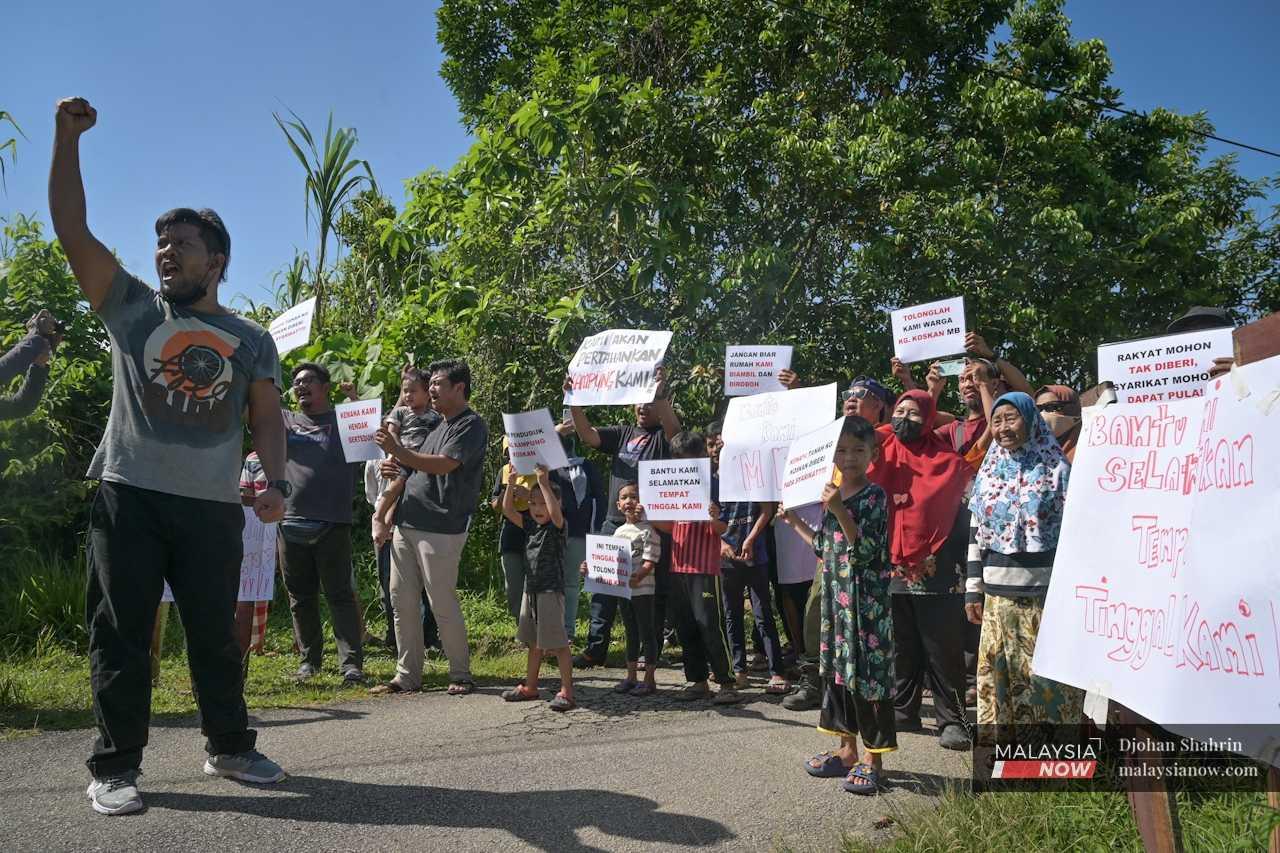 Villagers hold up signs, protesting the eviction order and the lack of official agreement about the residents themselves. 