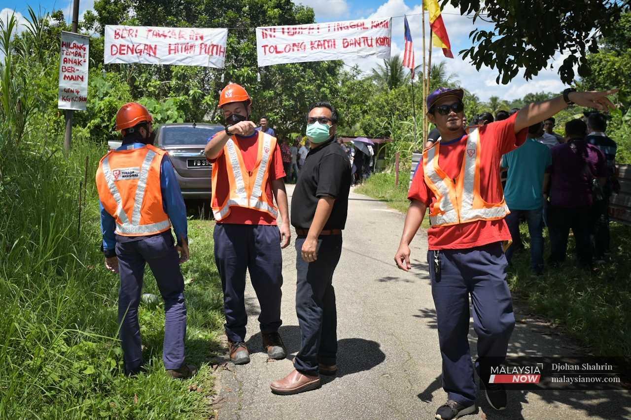 Workers from Tenaga Nasional Bhd arrive to cut the village's electricity supply.