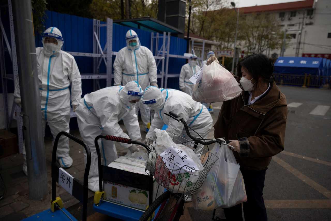 A woman delivers food to a residential compound under lockdown as outbreaks of Covid-19 continue in Beijing, China, Nov 28, 2022. Photo: Reuters