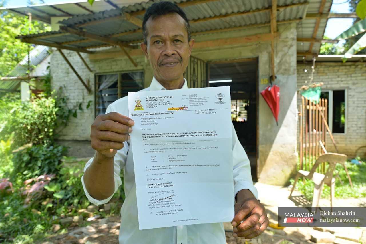 Penduduk Kampung Maszahar Hashim memegang sepucuk surat dari Pejabat Tanah Hulu Selangor yang menyatakan bahawa penduduk menduduki tanah persendirian meskipun mereka percaya ia tanah rizab kerajaan. 