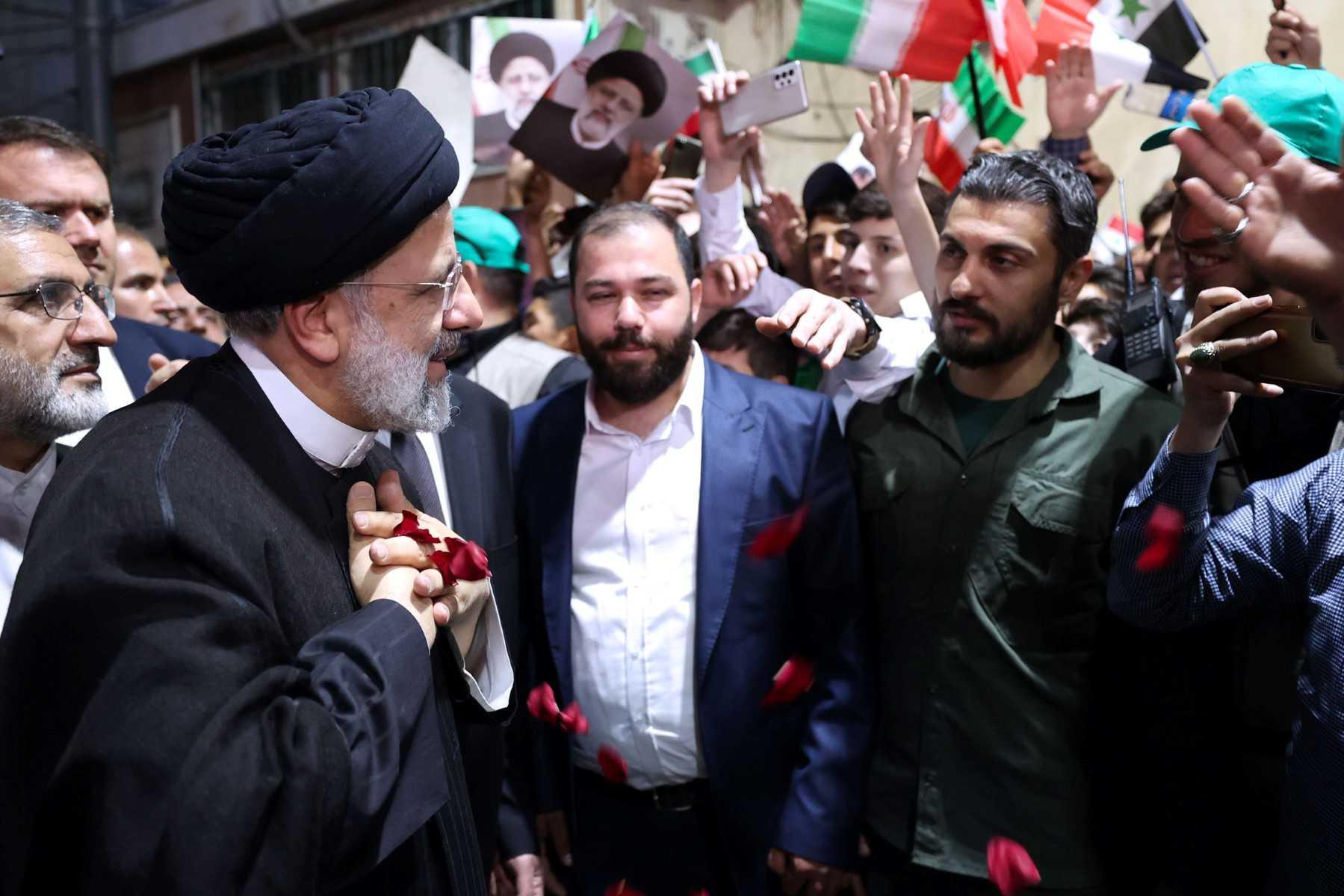 A handout picture provided by the Iranian presidency on May 4, shows Iranian President Ebrahim Raisi (left) greeting a group of men during his visit to the holy shrine of Sayyida Zaynab in the southern suburbs of Damascus. Photo: AFP 