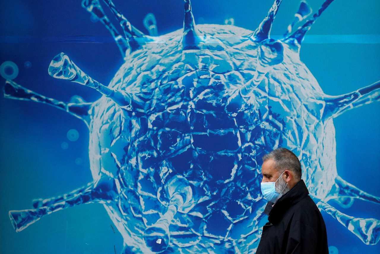 A man wearing a protective face mask walks past an illustration of a virus outside a regional science centre, amid the Covid-19 outbreak in Oldham, Britain, Aug 3, 2020. Photo: Reuters