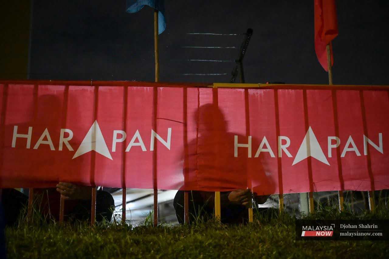 Party workers put up a Pakatan Harapan banner in this file photo taken ahead of the 15th general election in November 2022.