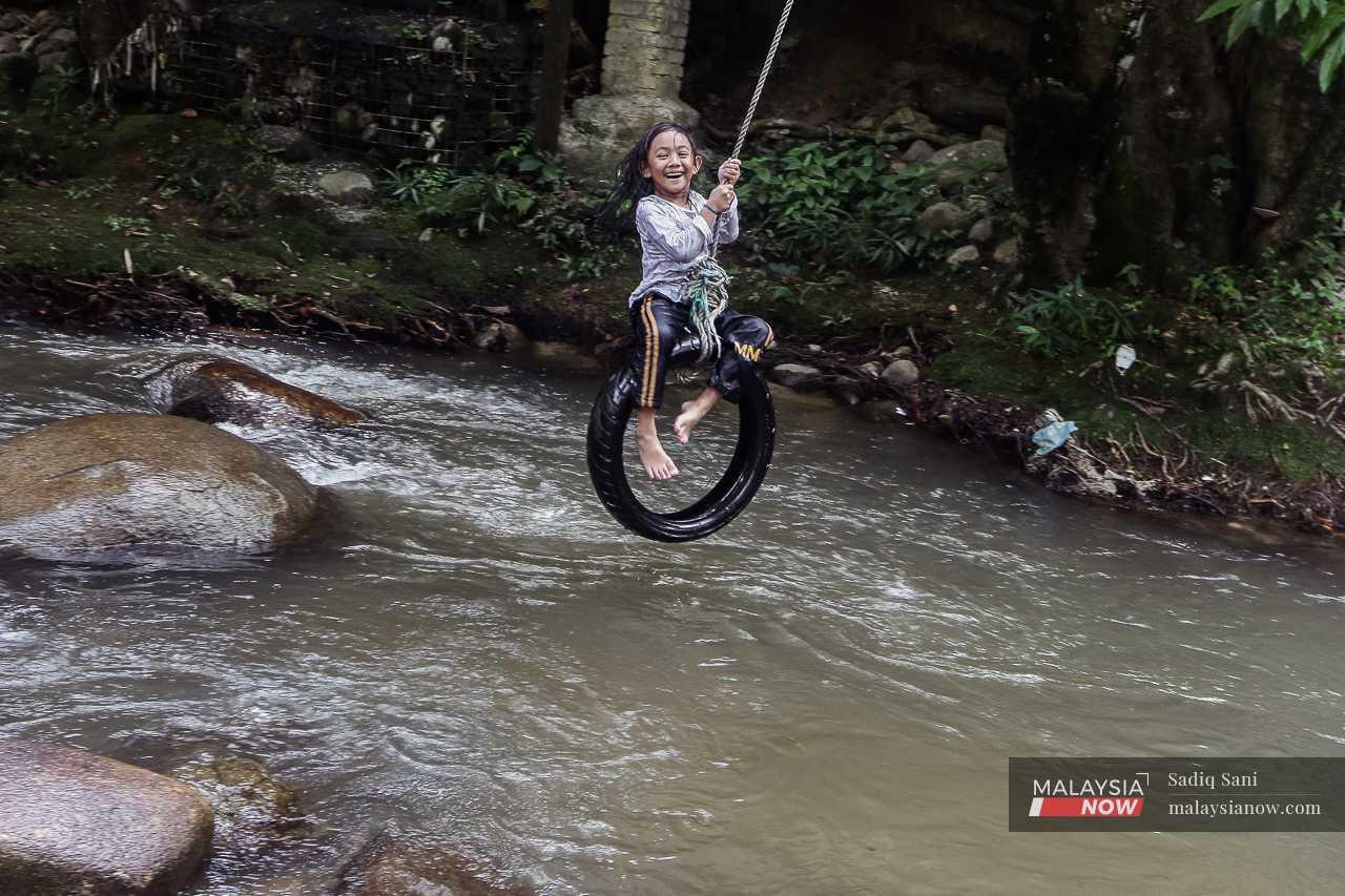 A girl laughs as she swings on a tyre suspended by a rope at a river in Hulu Langat, Selangor. 