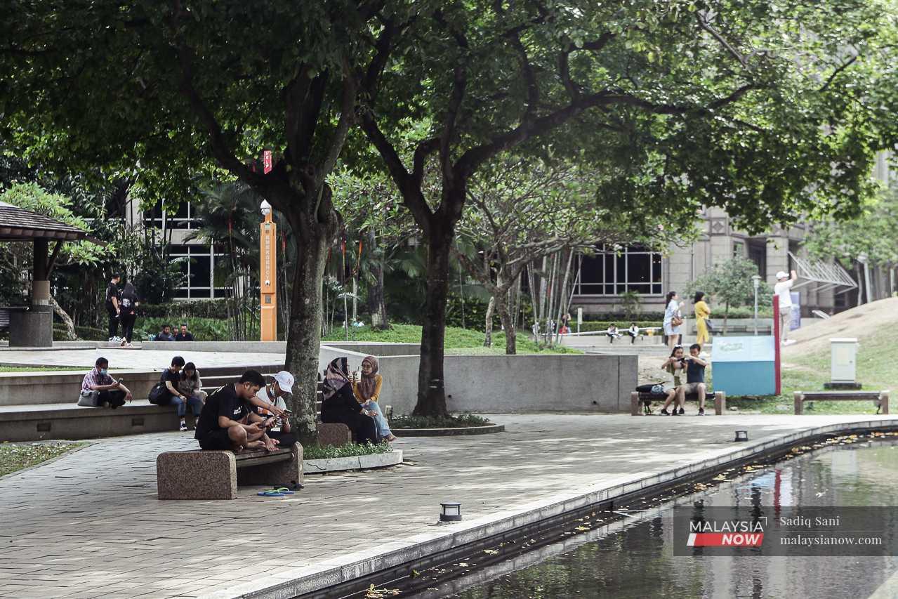 Pedestrians seek relief from the heat under a large tree in the capital city of Kuala Lumpur. 