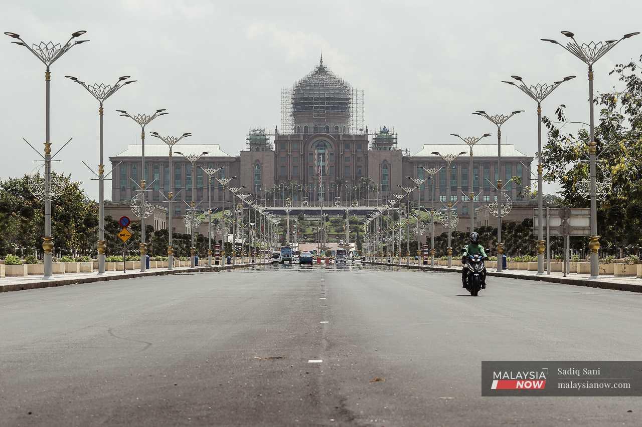 A mirage shimmers on the road as a motorcyclist passes the Prime Minister's Office on a hot day in Putrajaya. 