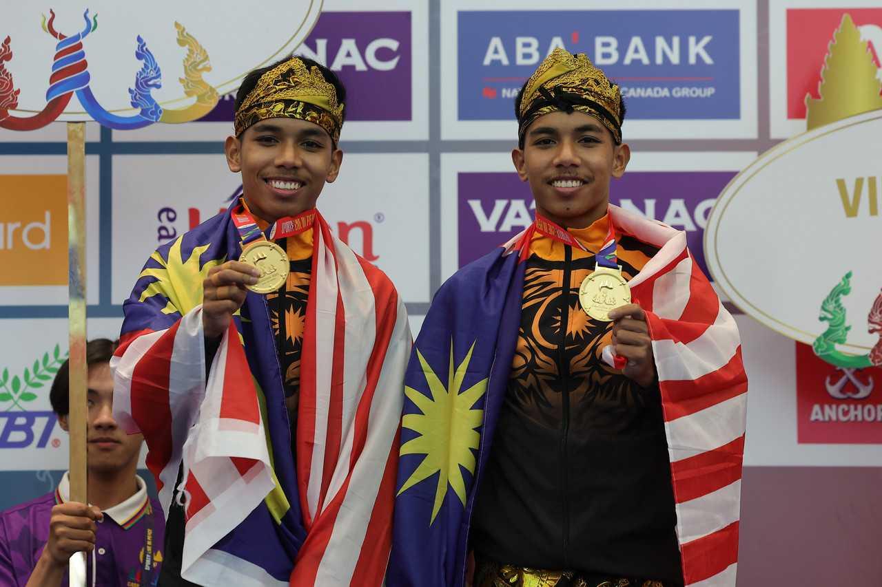 National silat athletes and twin brothers, Muhammad Danial Azrol Noorazizan (right) and Muhammad Danial Azray Noorazizan, display the gold medal they won in the artistic doubles event at the 2023 SEA Games at the Chroy Changvar Convention Center yesterday. Photo: Bernama