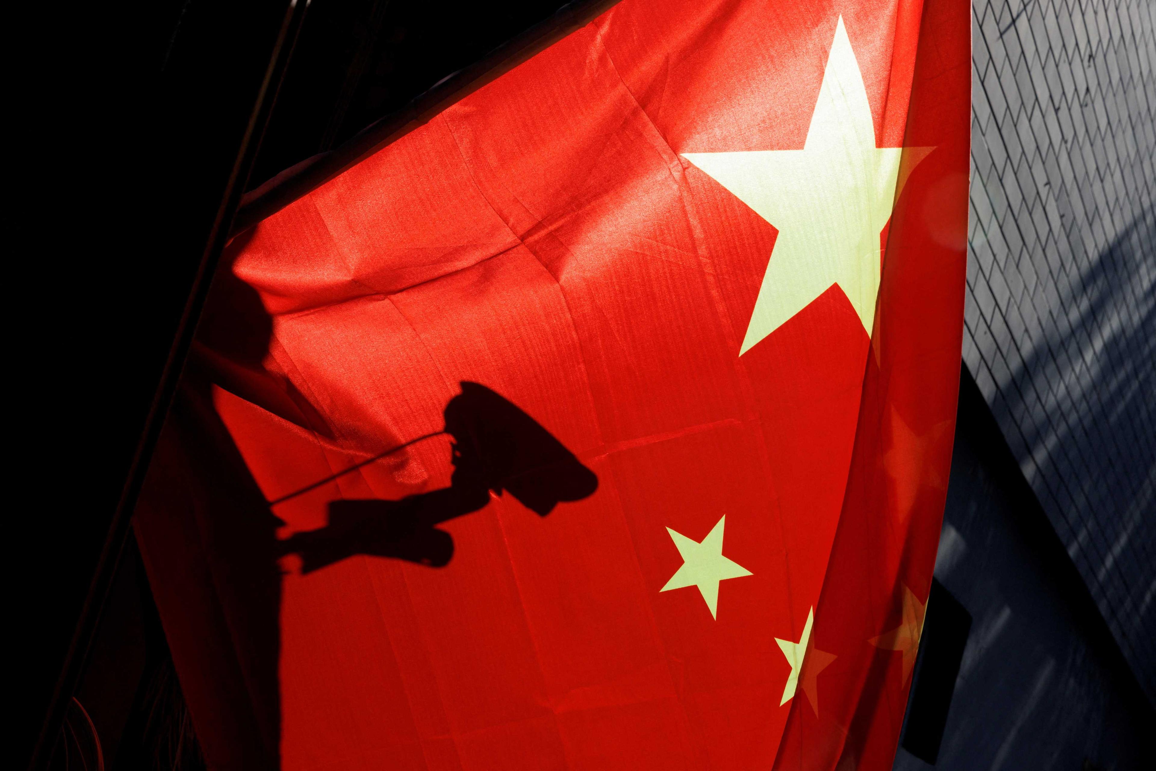 A surveillance camera is silhouetted behind a Chinese national flag in Beijing, China, Nov 3, 2022. Photo: Reuters