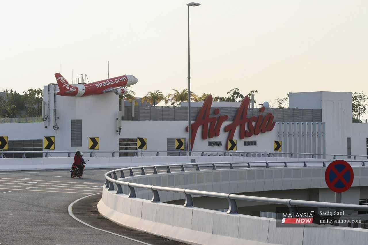 Penunggang motosikal melepasi papan iklan Air Asia di Sepang, 10 Februari 2022.