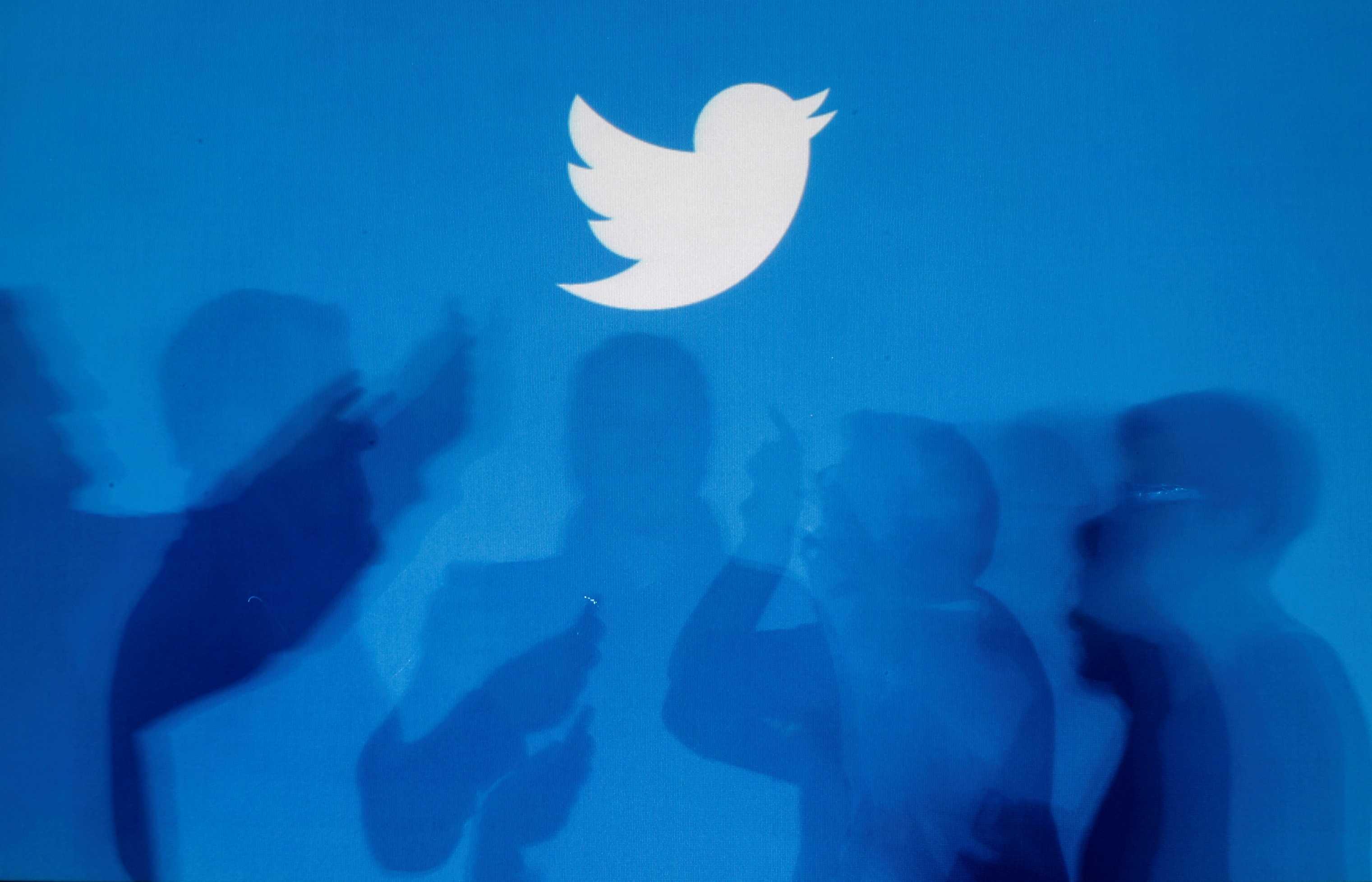 Bayang-bayang orang yang memegang telefon pintar dipaparkan pada latar belakang logo Twitter dalam gambar ilustrasi diambil di Warsaw 27 September 2013. Gambar: Reuters