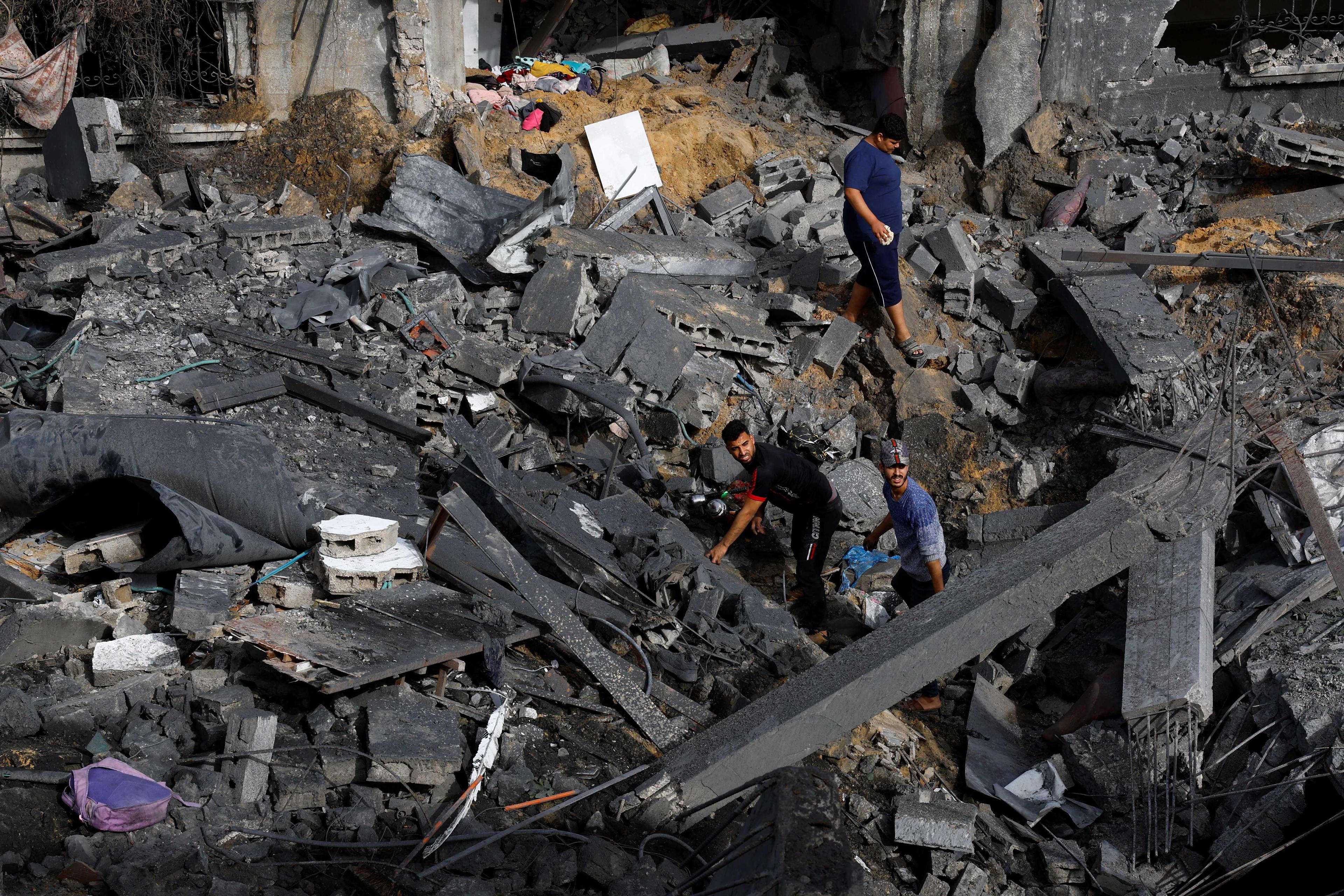 Orang ramai berjalan di dalam runtuhan, selepas serangan Israel, di utara Semenanjung Gaza pada 12 Mei. Gambar: Reuters