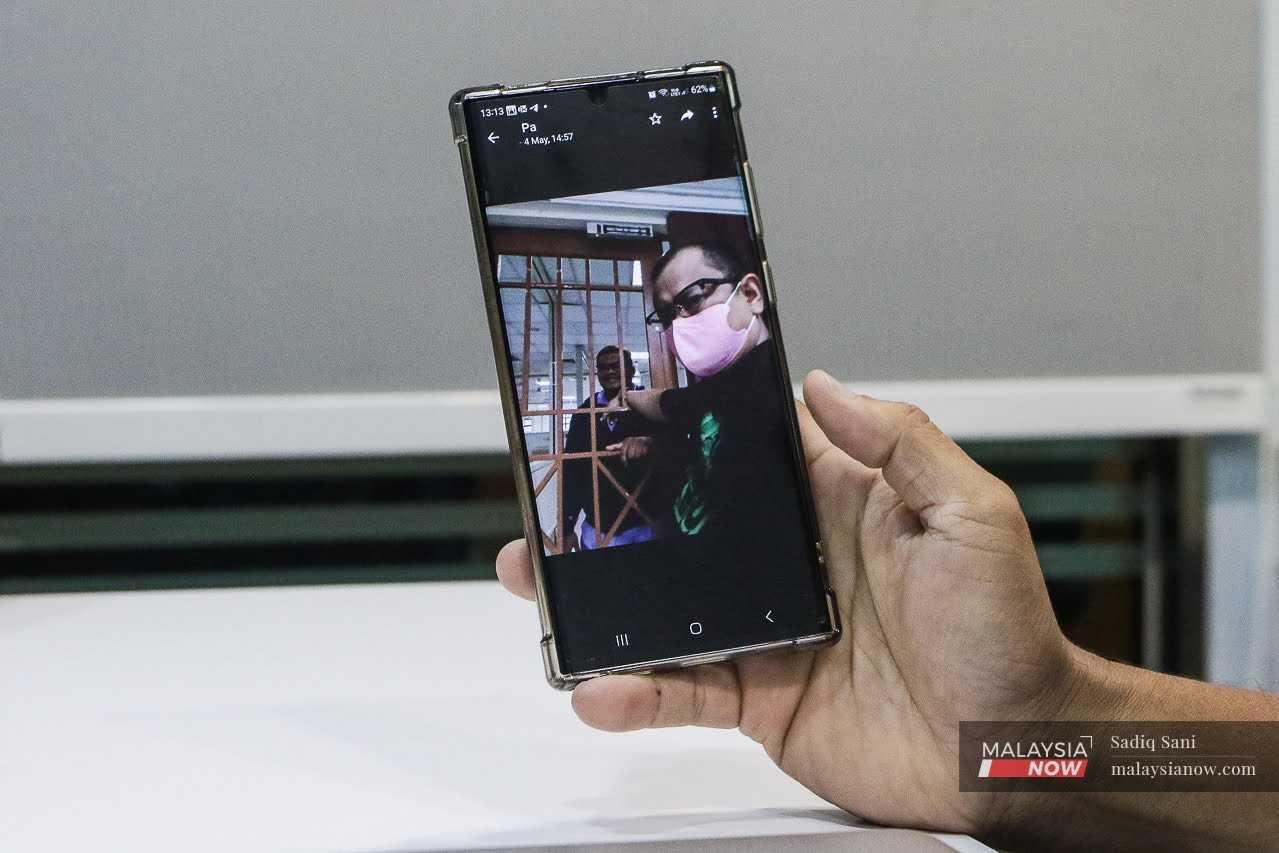 Mahathir Abdul Rahman shows a picture of his brother, Mustaza, with an officer at a prison where he was held under Sosma or the Security Offences (Special Measures) Act 2012.
