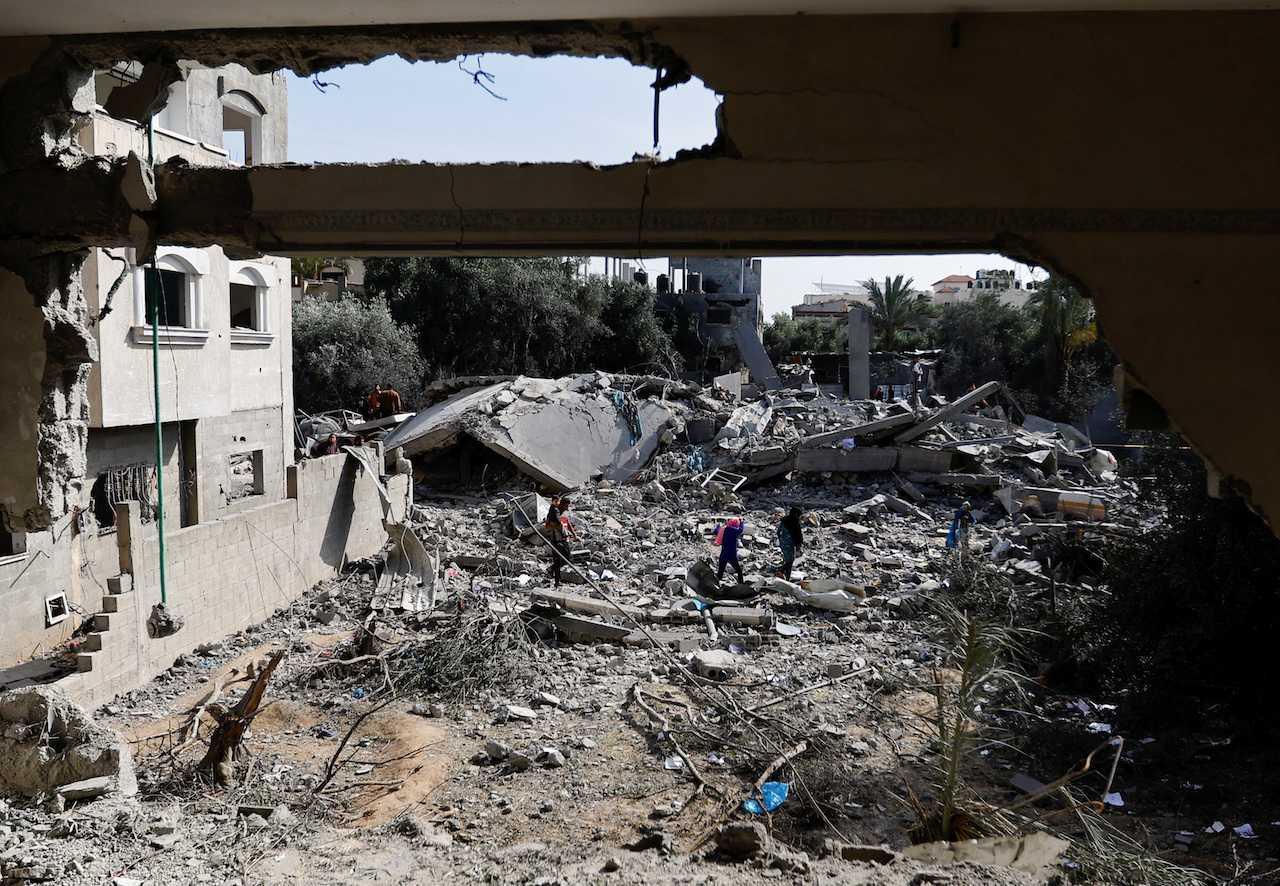 Palestinians walk among the rubble of buildings damaged in an Israeli strike during Israel-Gaza fighting, after a ceasefire was agreed between Palestinian factions and Israel, in Deir Al-Balah, central Gaza Strip, May 14. Photo: Reuters
