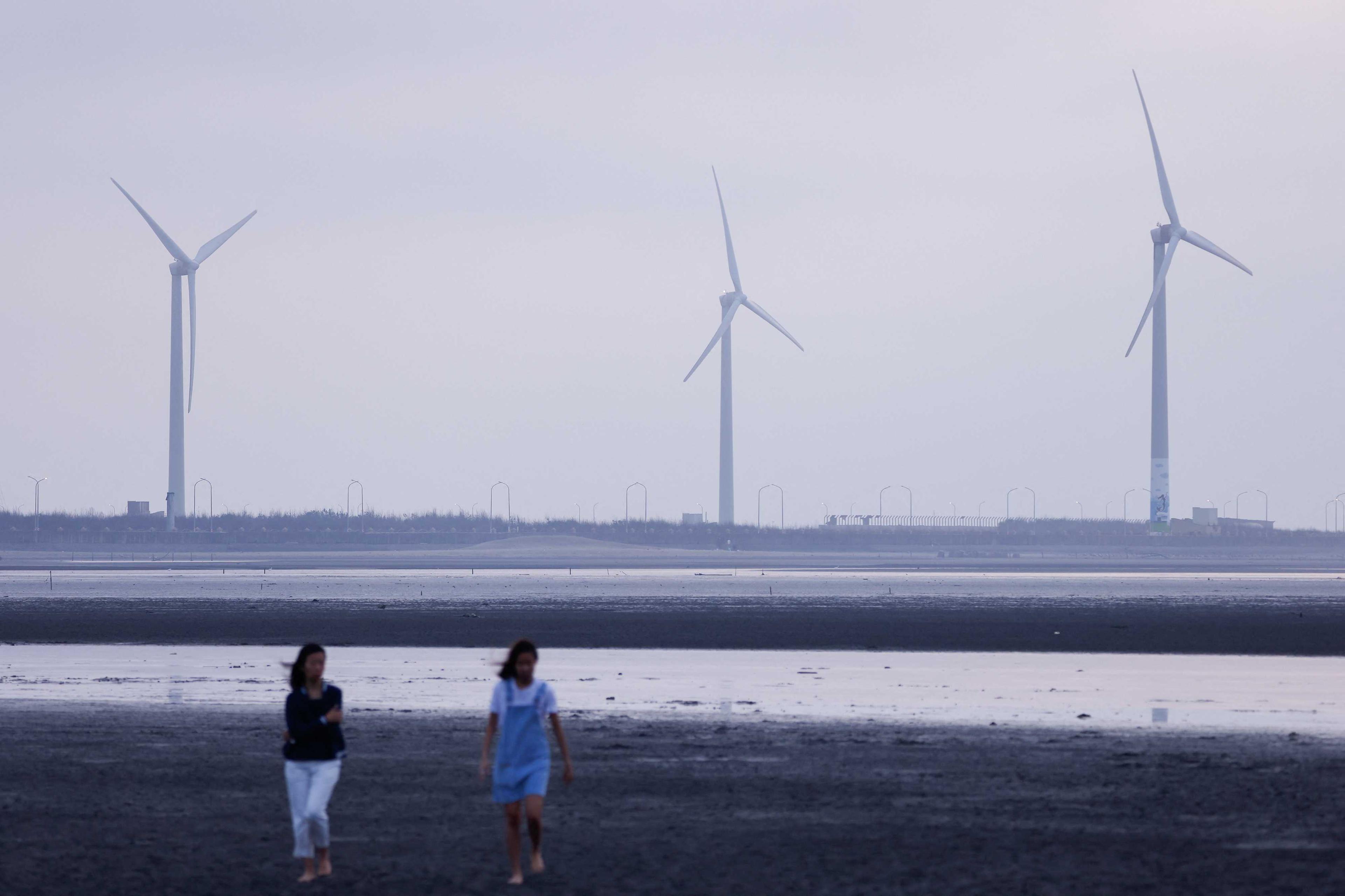 Tourists walk on the sand in front of wind turbines at Gaomei Wetlands in Taichung, Taiwan May 2. Photo: Reuters