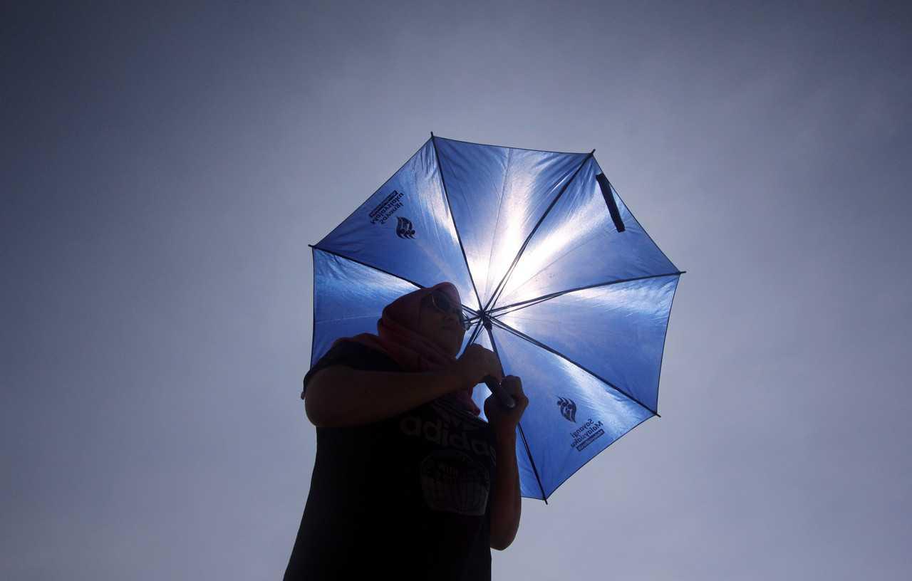 A woman uses an umbrella to shield herself from the scorching sun. Photo: Bernama