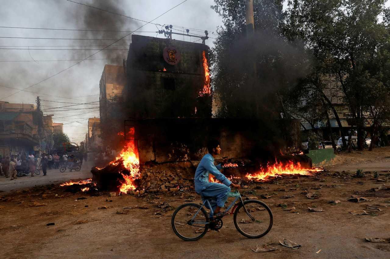 A boy rides past a paramilitary check post that was set on fire by the supporters of Pakistan's former prime minister Imran Khan, during a protest against his arrest, in Karachi, May 9. Photo: Reuters