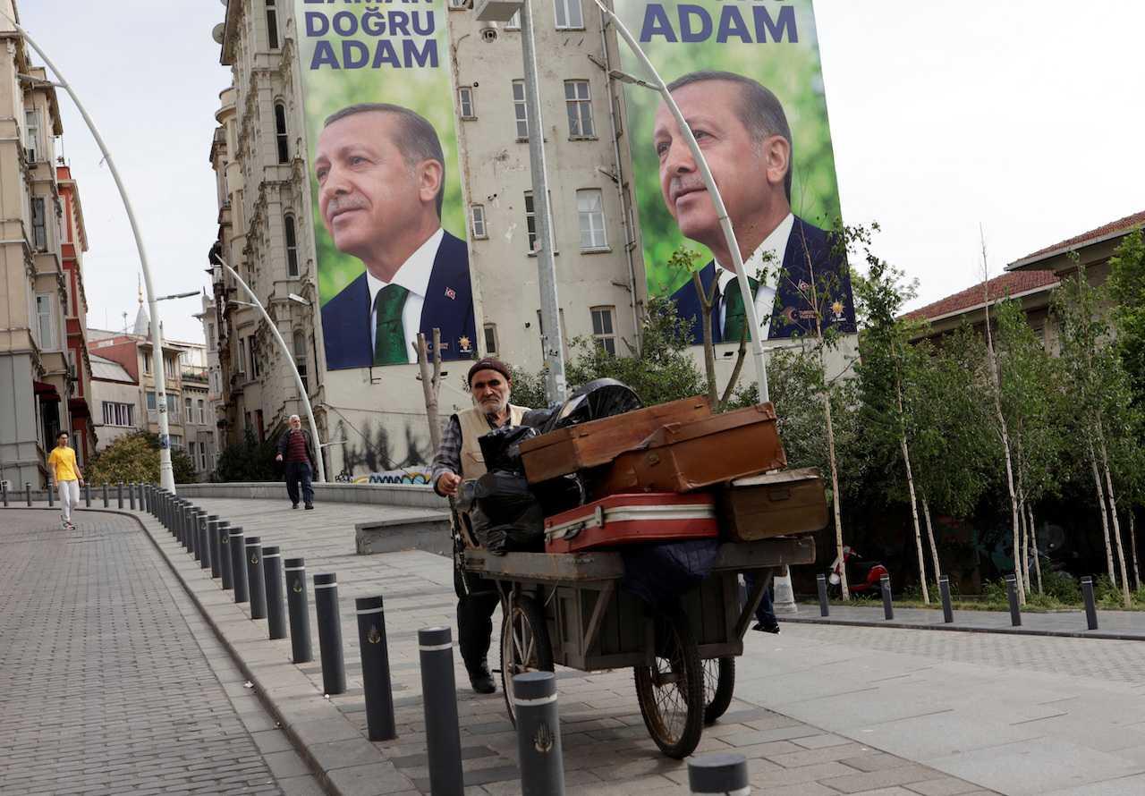 Seorang penjaja dengan poster kempen pilihan raya Presiden Recep Tayyip Erdogan di belakangnya, selepas pusingan pertama pilihan raya presiden dan Parlimen, di Istanbul, Turkiye, 15 Mei. Gambar: Reuters