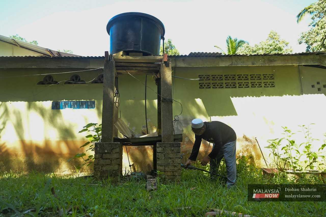 A villager checks the water pump at his house in Kampung Bongor, Gerik. 
