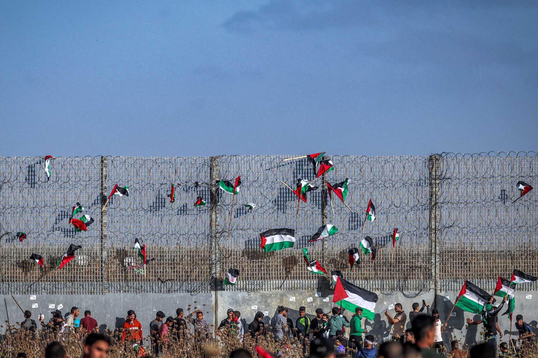 Palestinian flags are fixed to the barbed-wire fence during a 'flag march' demonstration along the border with Israel east of Gaza city on May 18, in response to the annual Israeli flag march marking 'Jerusalem Day' commemorating the old city's capture by Israel. Photo: AFP 