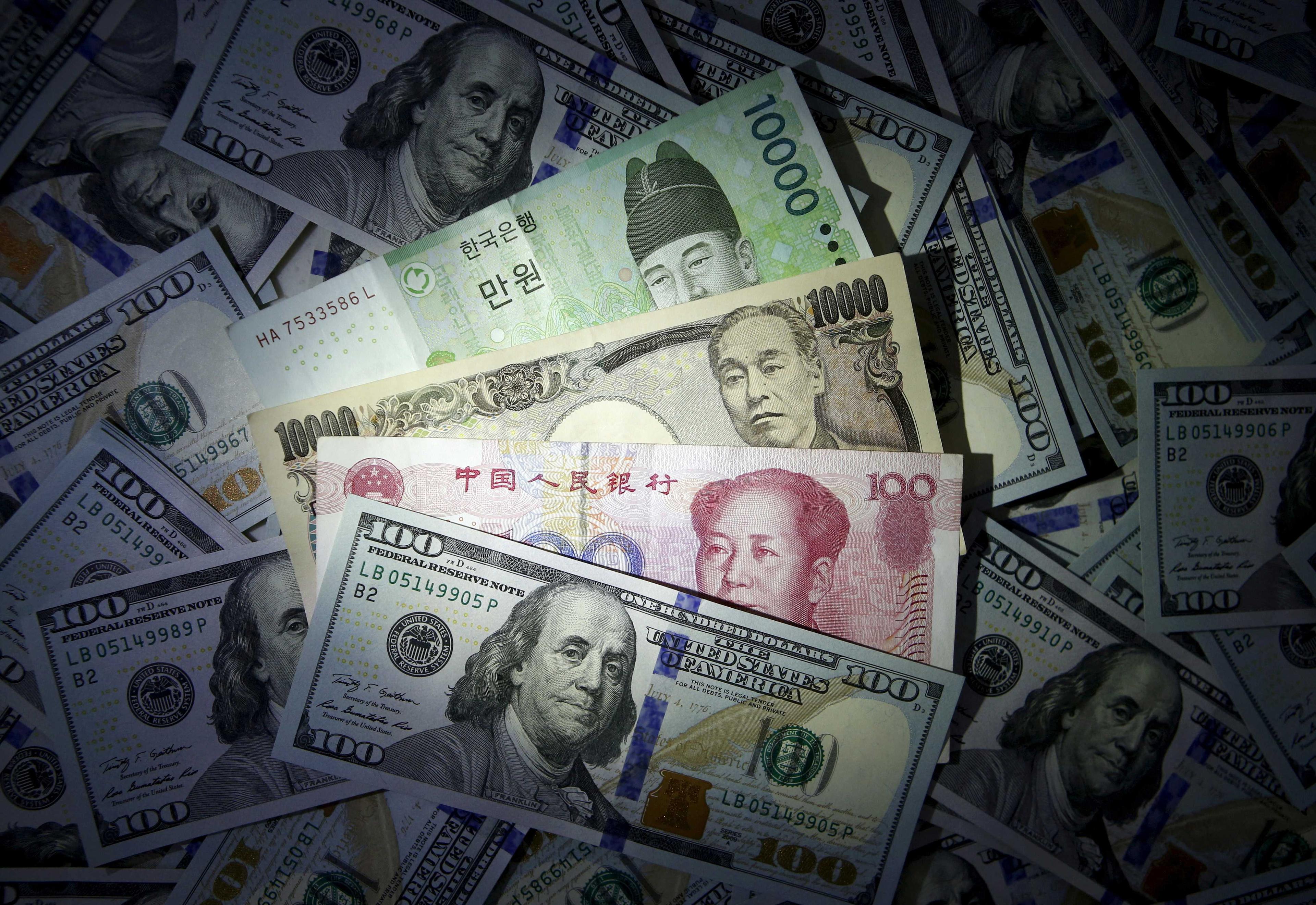 South Korean won, Chinese yuan and Japanese yen notes are seen on US 100 dollar notes in this illustration shot Dec 15, 2015. Photo: Reuters
