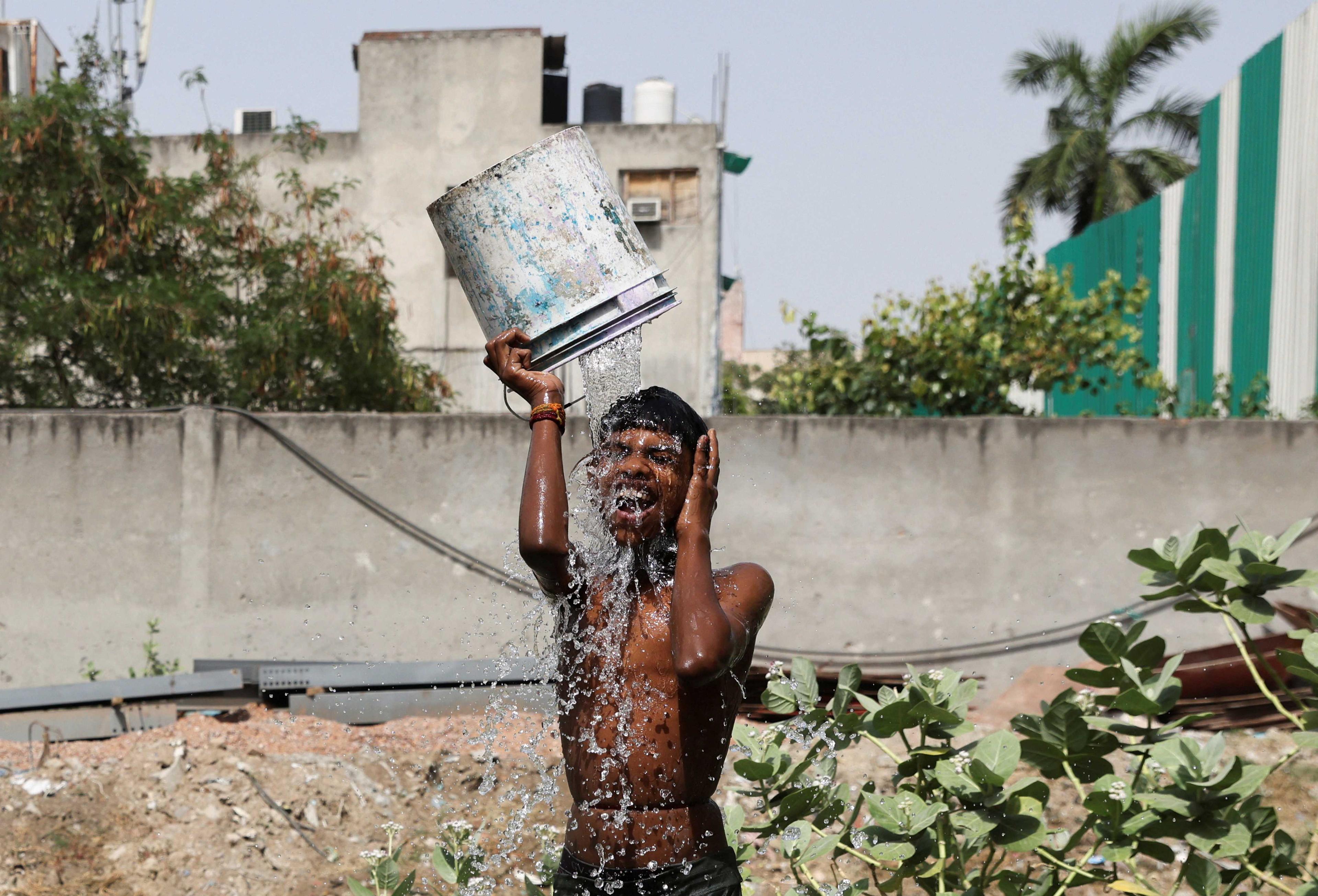 Seorang kanak-kanak lelaki mandi di luar kediamannya susulan gelombang haba melanda New Delhi di India, 22 Mei. Gambar: Reuters