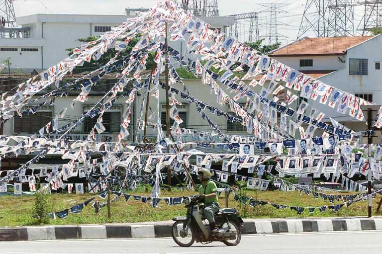 A motorcyclist drives past a garden filled with election campaign banners for DAP and Barisan Nasional in Kuala Lumpur, in this Nov 25, 1999 file picture. Photo: AFP
