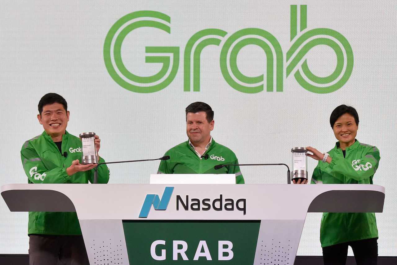 Grab CEO Anthony Tan and co-founder Tan Hooi Ling hold up the Nasdaq Crystal received from the chairman of Nasdaq Apac, Robert McCooey, at the Grab Bell Ringing Ceremony, at a hotel in Singapore, Dec 2, 2021. Photo: Reuters