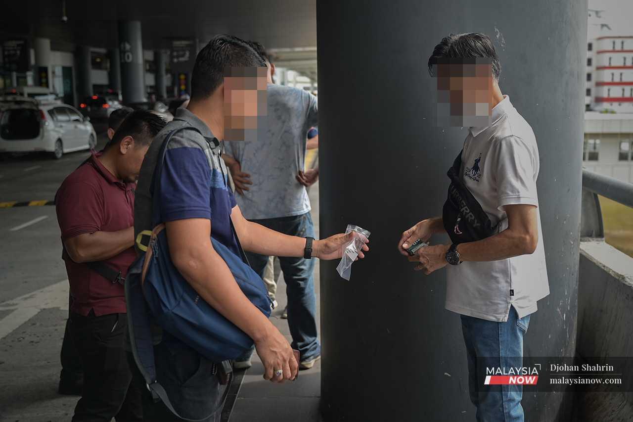 Seorang pegawai berpakaian biasa menghulurkan beg plastik selepas terserempak dengan pesalah lain. 