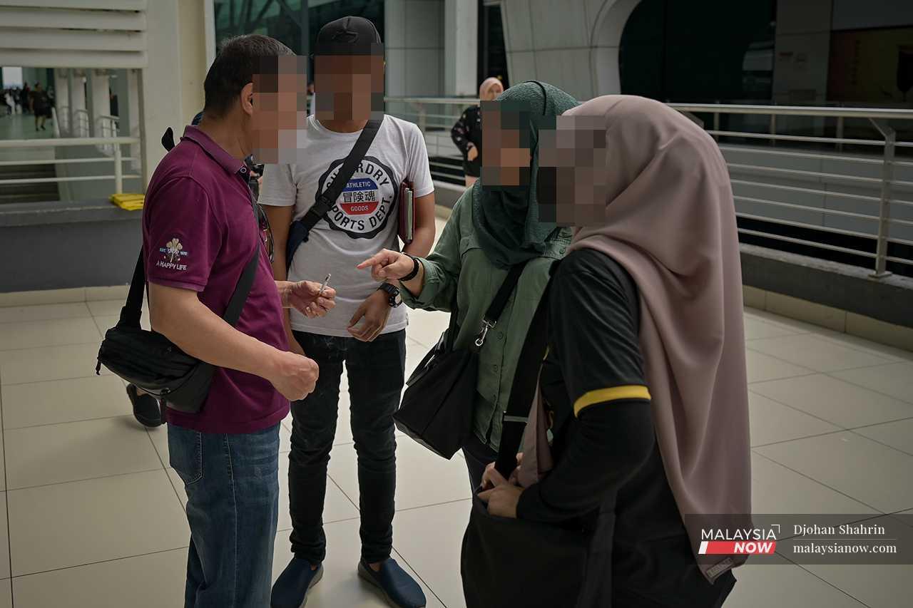 Enforcement officers speak with an international traveller who is smoking in a public area before issuing him a notice. 
