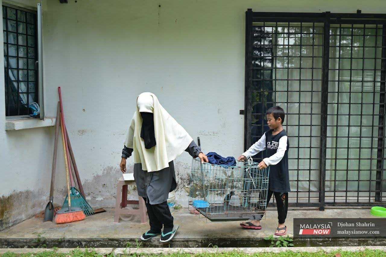 Noraidah Abdul Ghani and her young son clean out a cat's cage at their home in Serendah, Rawang.
