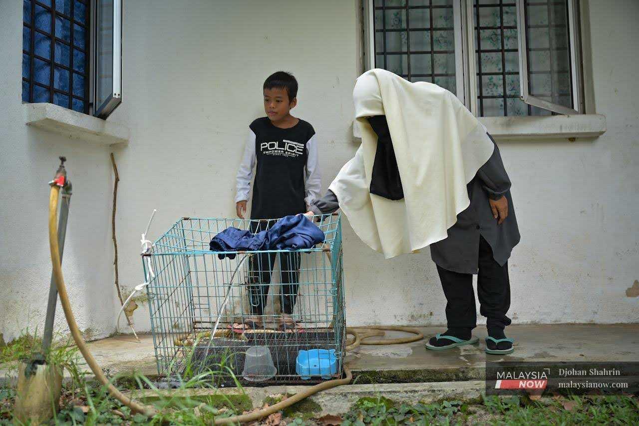 Noraidah Abdul Ghani ditemani anaknya Abdul Rahman, 10, melakukan rutin harian membersihkan kandang kucing di Serendah, Rawang.