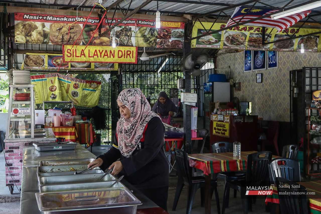 A restaurant worker prepares food for customers at an earty in Kampung Felda Sendayan in Bandar Sri Sendayan, Negeri Sembilan.
