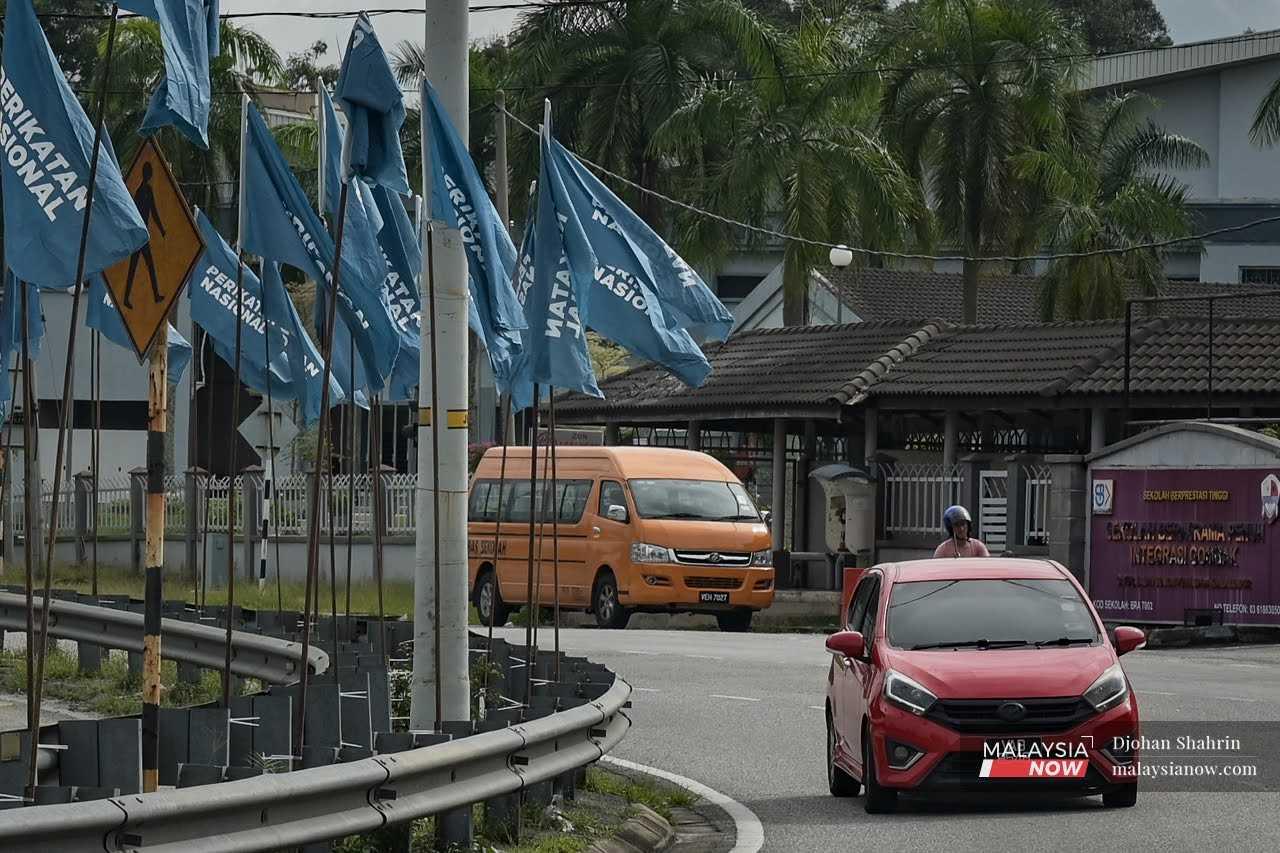 Sebuah kereta melalui berhampiran deretan bendera Perikatan Nasional yang tergantung di Jalan Sungai Pusu, Gombak, Selangor.